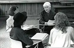 Douglass and students sitting at student desks arranged in a small circle in a classroom
